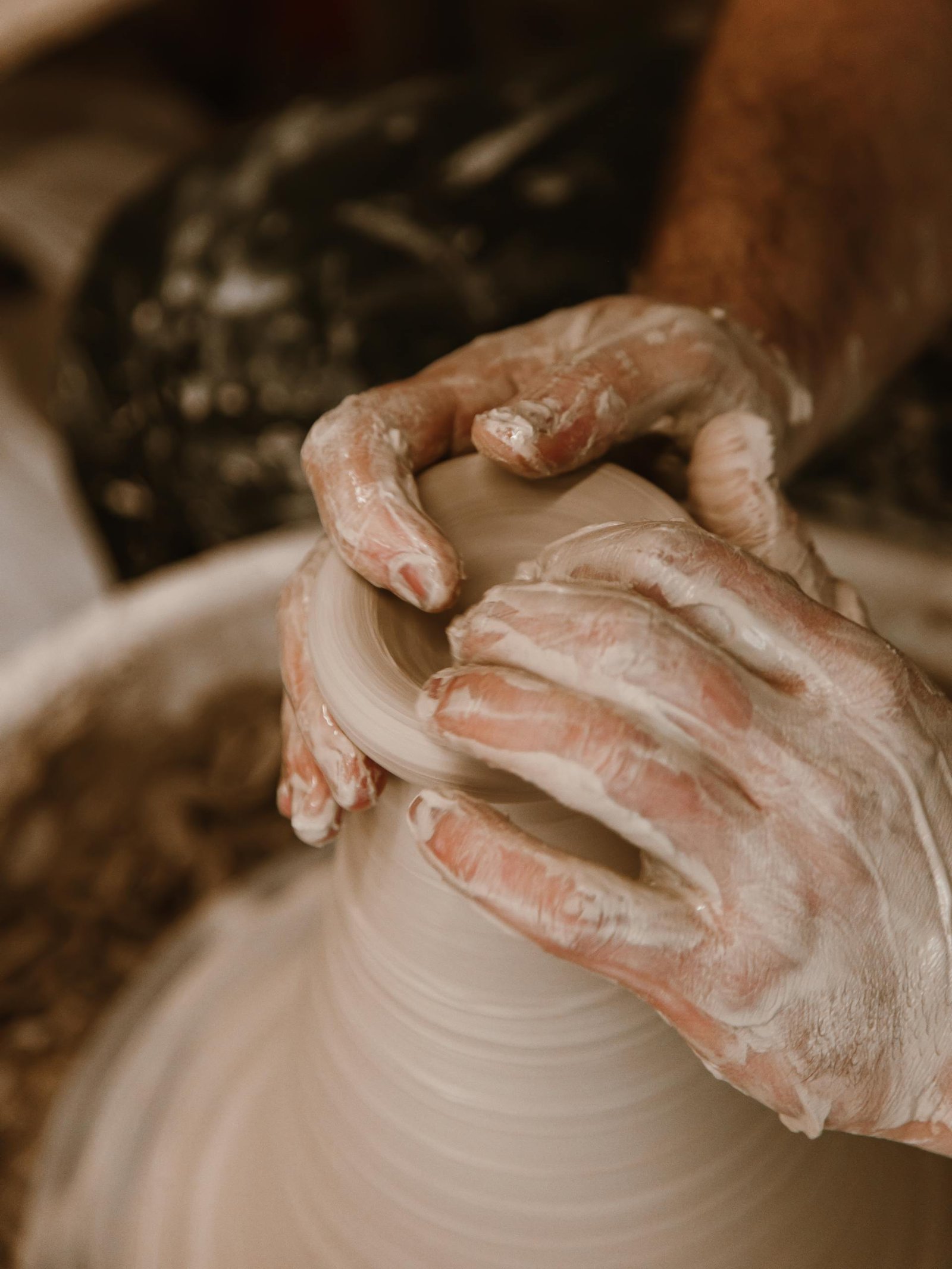 Artisan hands skillfully shaping wet clay on a pottery wheel, focusing on authentic craftsmanship.